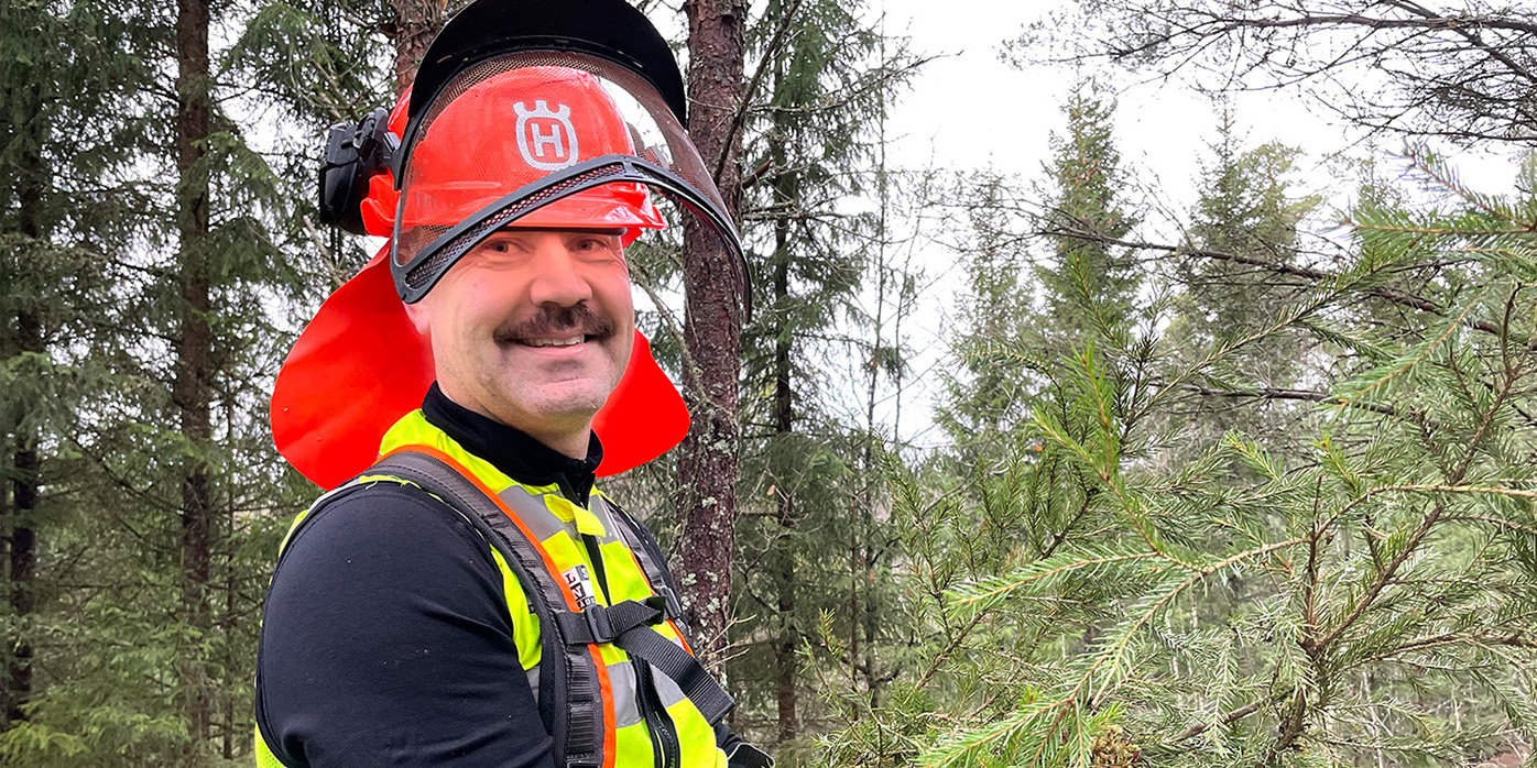 Skogsmaskinsförare står ute i skogen.